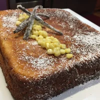 Pan de Elote 21 Porción de pan de elote decorado con granos de elote y azúcar glass, acompañado de salsa de rompope