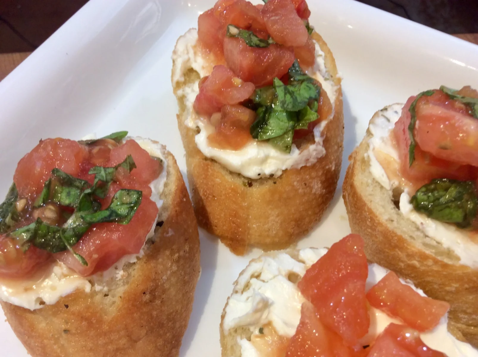 Italian Bruschettas on a wooden board with tomatoes, feta cheese and fresh basil