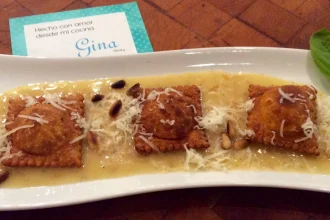 Raviolis de pimiento asado acompañados de salsa Beurre Blanc y decorados con piñones tostados.