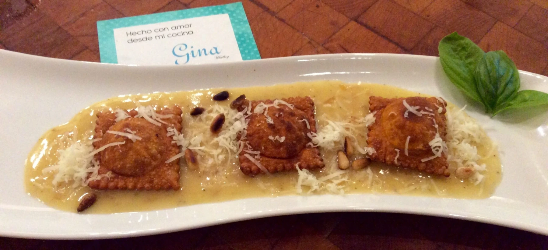 Roasted pepper ravioli accompanied by Beurre Blanc sauce and garnished with toasted pine nuts.