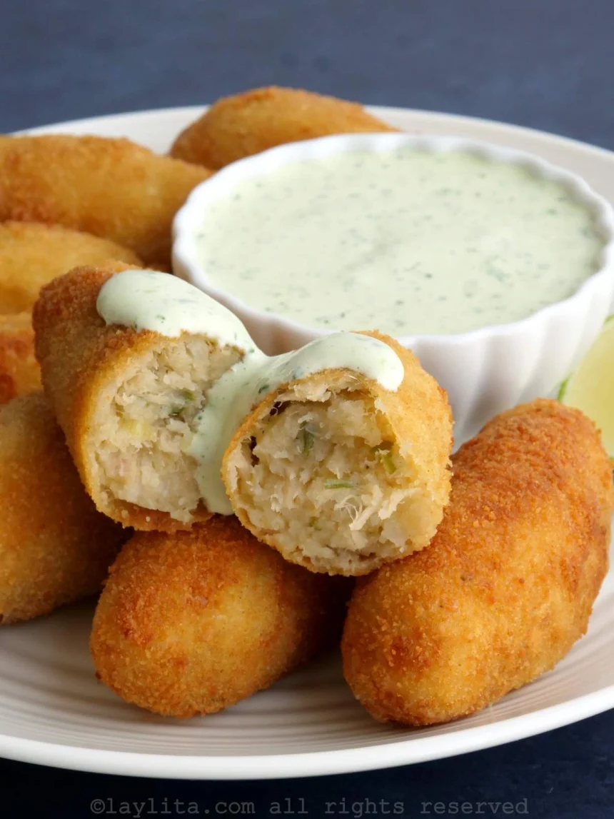 Plato con croquetas doradas de bacalao acompañadas de alioli de cilantro en un recipiente decorativo