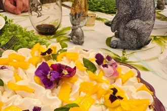 Pay de mango con base crujiente, relleno cremoso y decoración de crema batida, mango fresco y flores comestibles