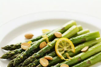 Espárragos tibios salteados con limón confitado y almendras tostadas servidos en plato elegante
