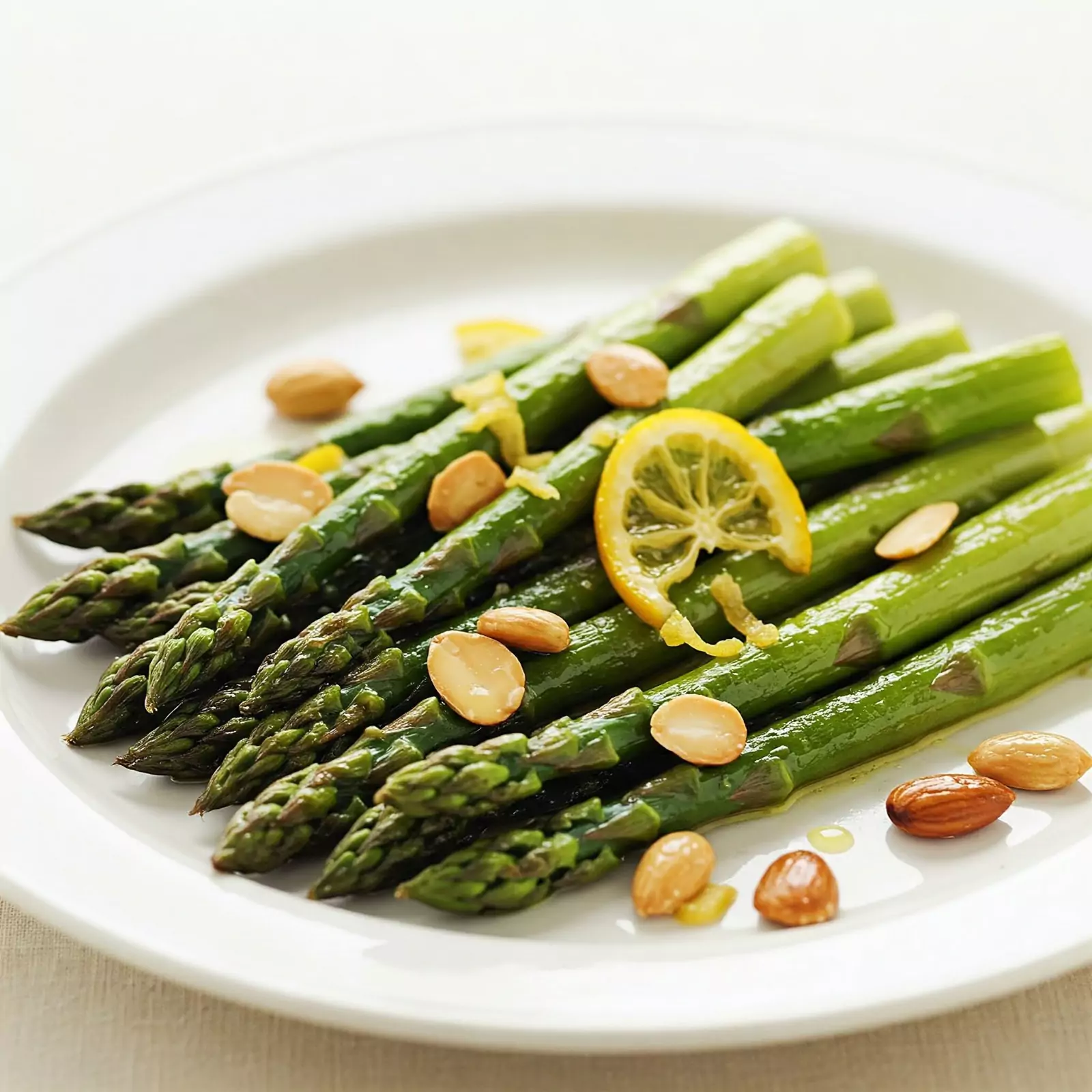 Espárragos tibios salteados con limón confitado y almendras tostadas servidos en plato elegante