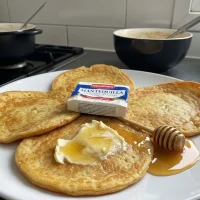 Crepas francesas clásicas apiladas en plato blanco con mantequilla y miel