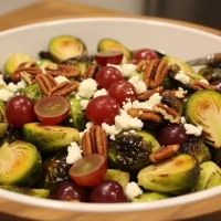 Coles de Bruselas, uvas, pecanas y cotija (vinagreta maple–chipotle)